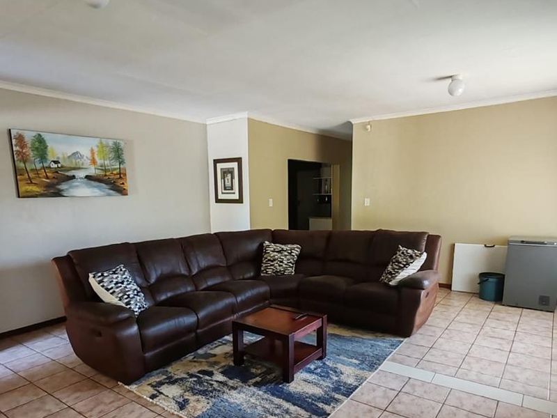 Spacious living area featuring neutral wall tones, ceramic tiled flooring, and simple ceiling lighting, offering a functional layout for comfortable family living.