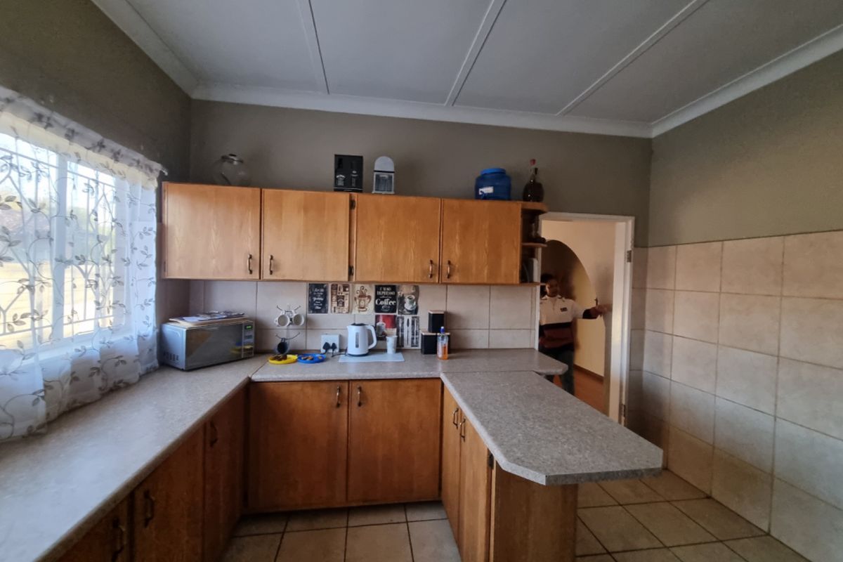 A functional kitchen featuring wooden cabinetry, laminate countertops, and tiled flooring, offering a practical layout with potential for modern updates.