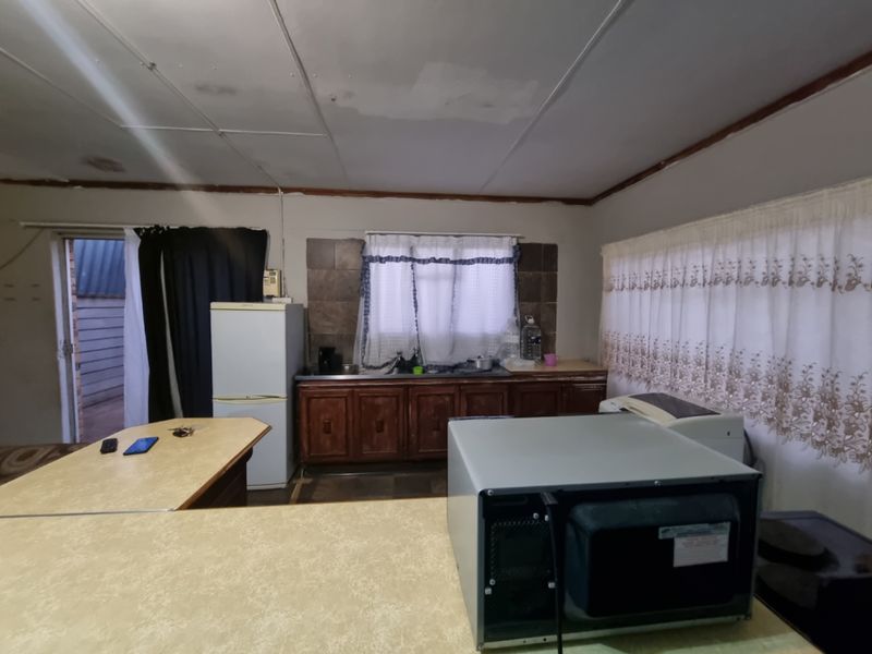 A dated kitchen area featuring built-in cabinetry, laminate countertops, and a tiled backsplash, requiring cosmetic updates to improve the overall aesthetic and functionality.