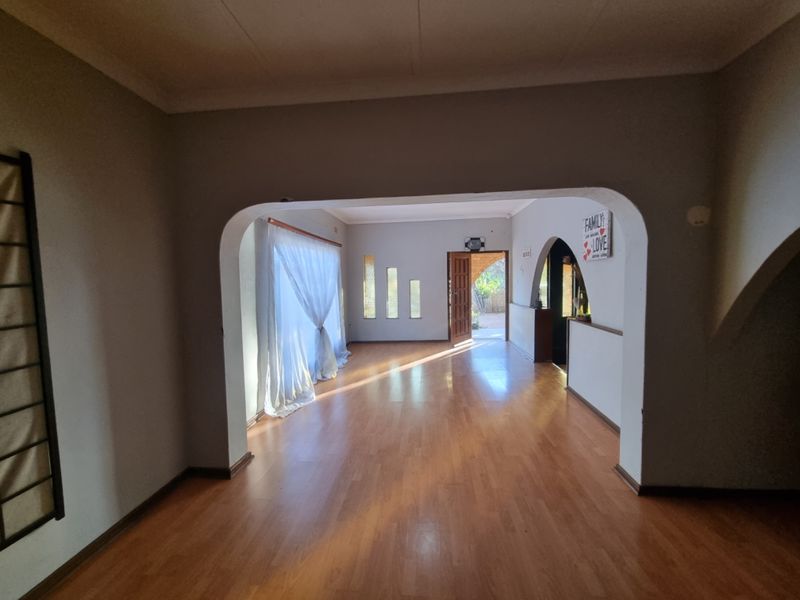 Spacious living area featuring laminate flooring, distinctive arched doorways, and decorative wall niches, leading to an exterior entrance.
