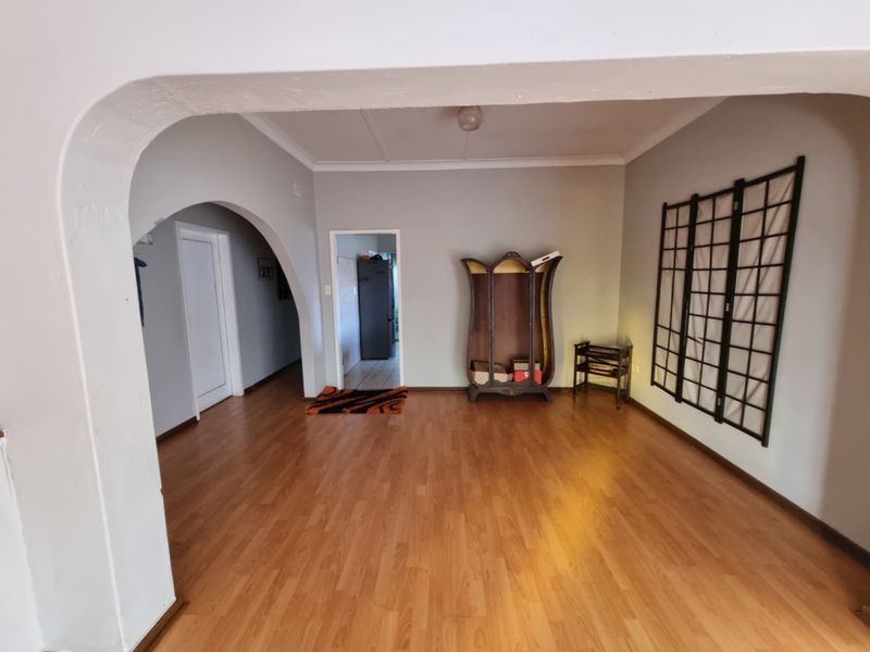 Spacious living area featuring laminate flooring, a distinctive arched doorway, and coved ceilings, offering a neutral canvas for interior design.