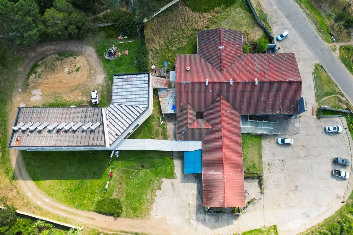 Aerial view of a commercial property complex featuring multiple connected buildings with pitched tiled roofs, paved parking areas, and surrounding grounds.