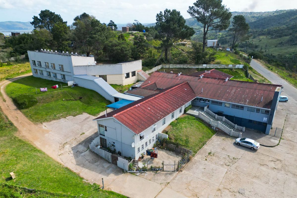 Aerial view of a commercial property complex featuring multiple connected buildings with red tiled roofs, concrete paved areas, and surrounding landscaped grounds.
