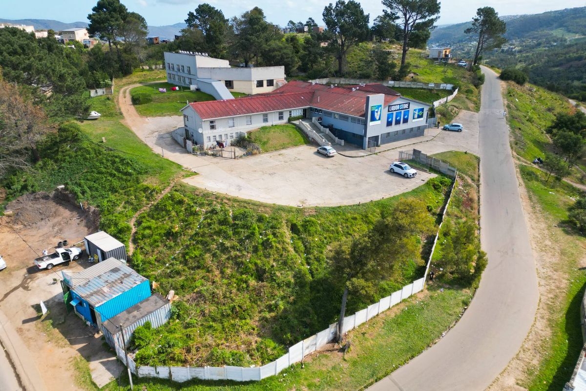 Aerial view of a commercial property featuring a main building with a liquor store, paved parking area, and surrounding landscaped grounds.
