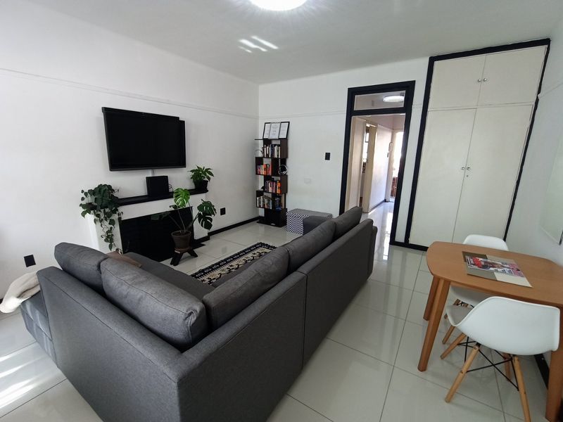 Open-plan living area featuring tiled flooring, a fireplace, and built-in storage cupboards, providing a functional and well-maintained space.