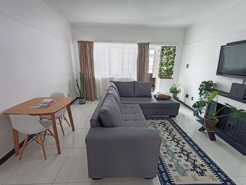 A bright living room featuring white tiled flooring, a fireplace, and a picture rail, offering a clean and functional space.