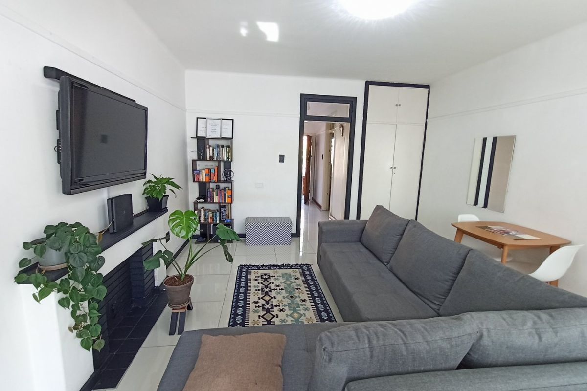 A bright living room featuring tiled flooring, a fireplace, and built-in storage cupboards, offering a clean and functional living space.