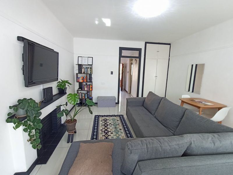 A bright living room featuring tiled flooring, a fireplace, and built-in storage cupboards, offering a clean and functional living space.
