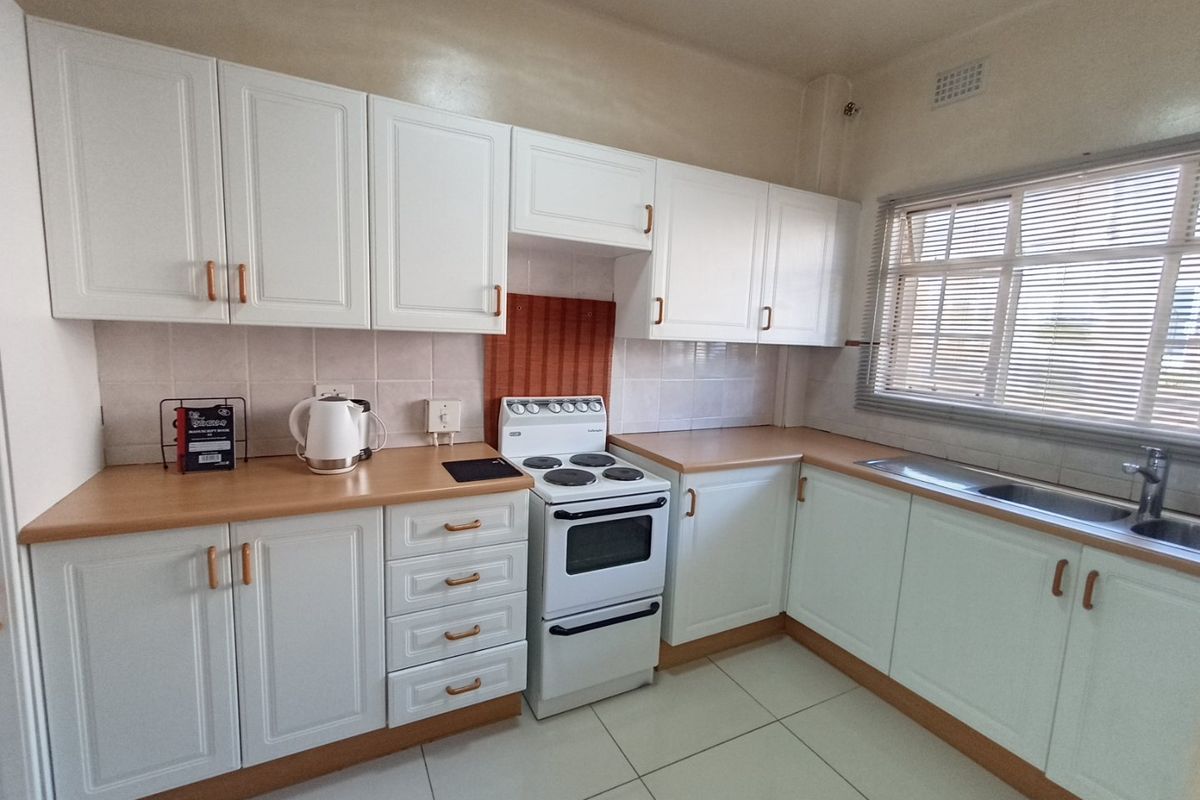 A clean and functional kitchen featuring white cabinetry, laminate countertops, a tiled backsplash, and a freestanding stove with a double oven.