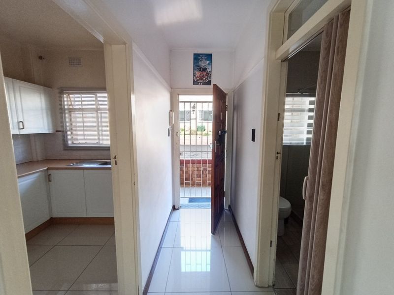 A bright entrance hallway with tiled flooring, providing access to the kitchen and bathroom areas, featuring a secure entrance door and intercom system.