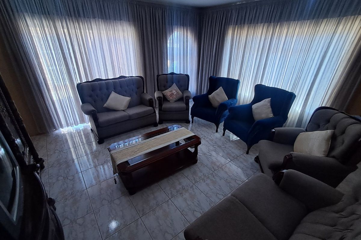 A living room featuring tiled flooring and floor-to-ceiling curtains, providing a neutral base for interior design updates.