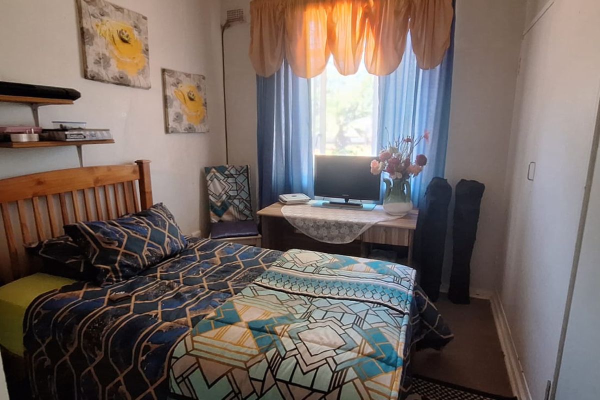 A compact bedroom featuring a built-in wardrobe and a window, providing a functional space with standard finishes.