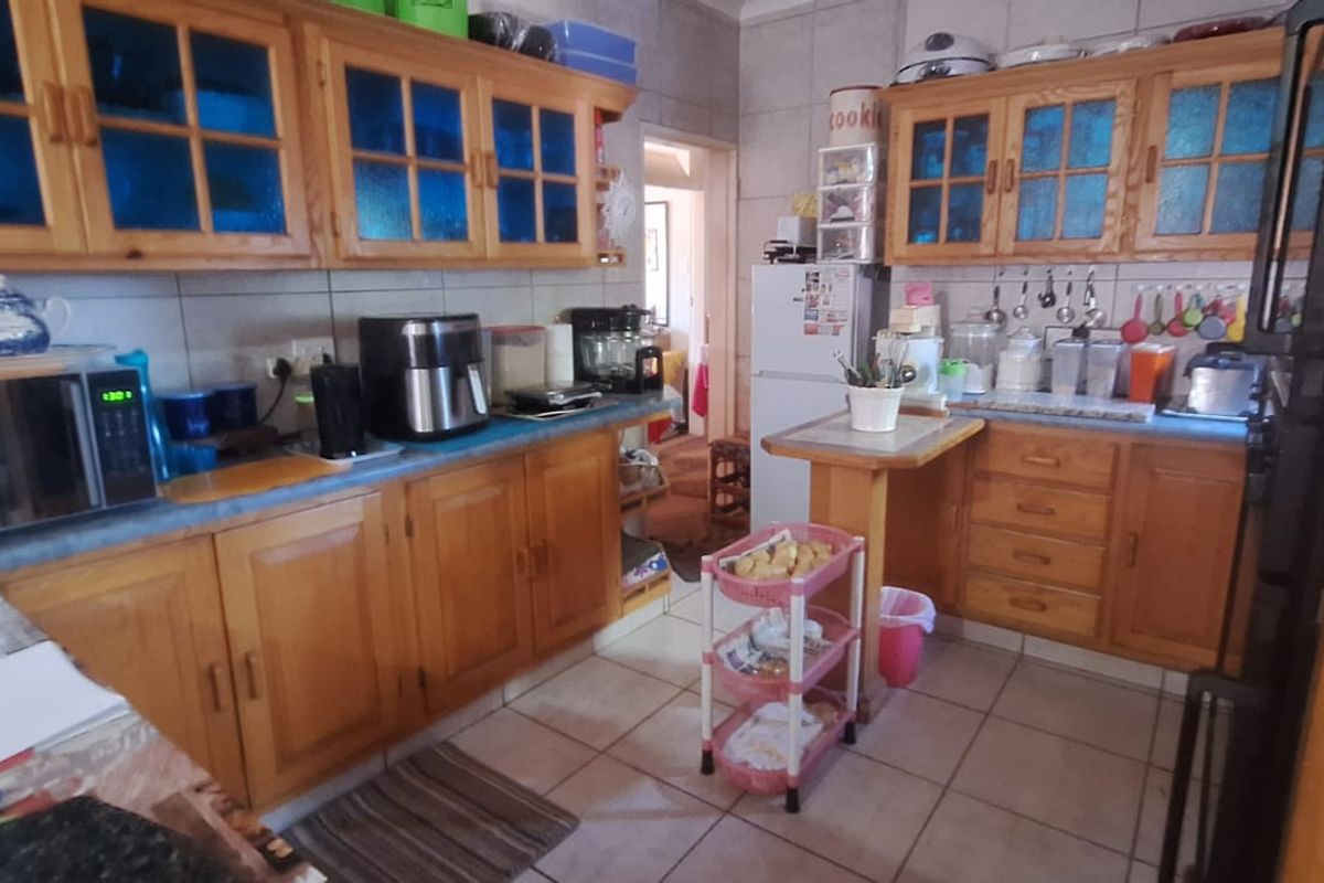 A functional kitchen featuring traditional wooden cabinetry, tiled flooring, and ample counter space, offering a classic layout ready for modern updates.