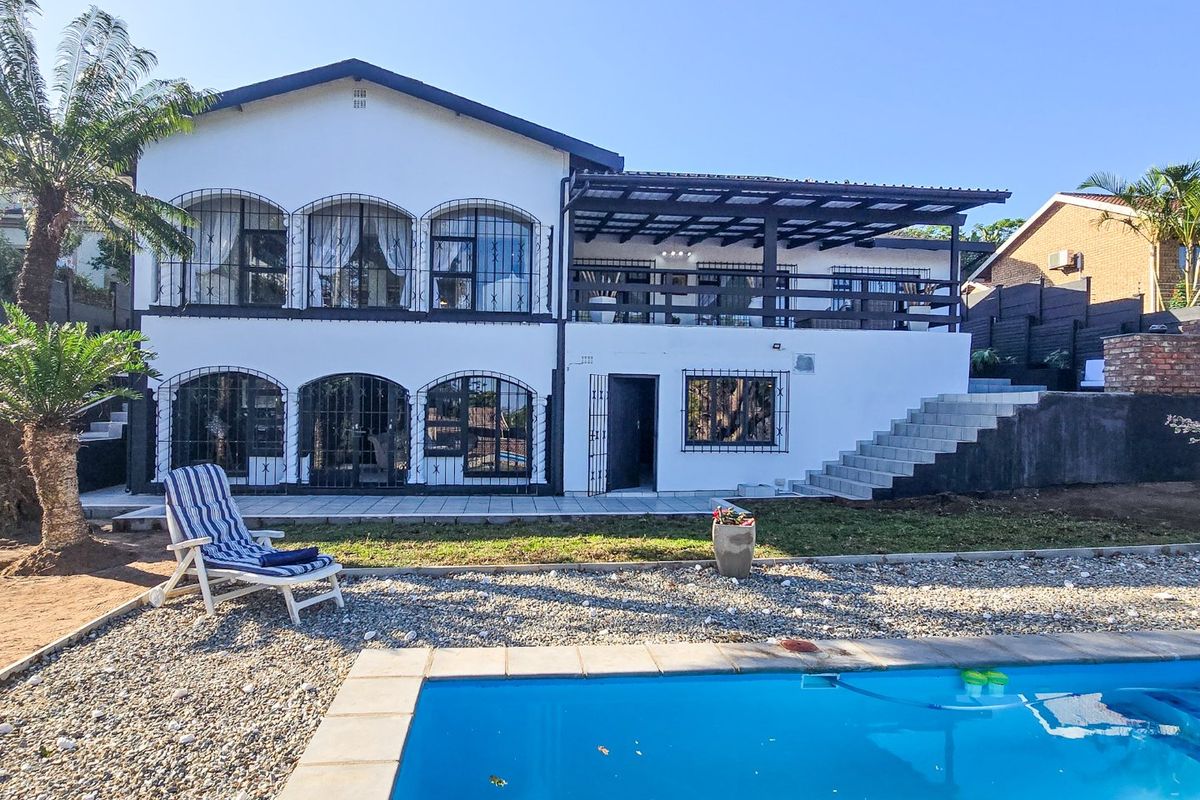 Rear view of a two-story house featuring a swimming pool, a covered patio area, and security bars on the windows.