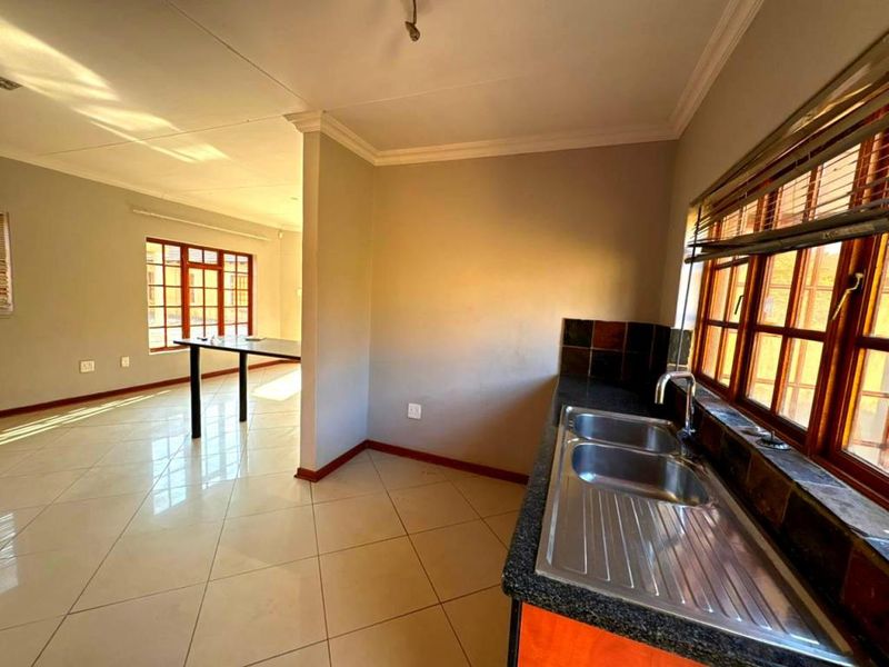 Open plan kitchen and living area featuring tiled flooring, a double sink, and a breakfast bar, offering a functional layout for modern living.