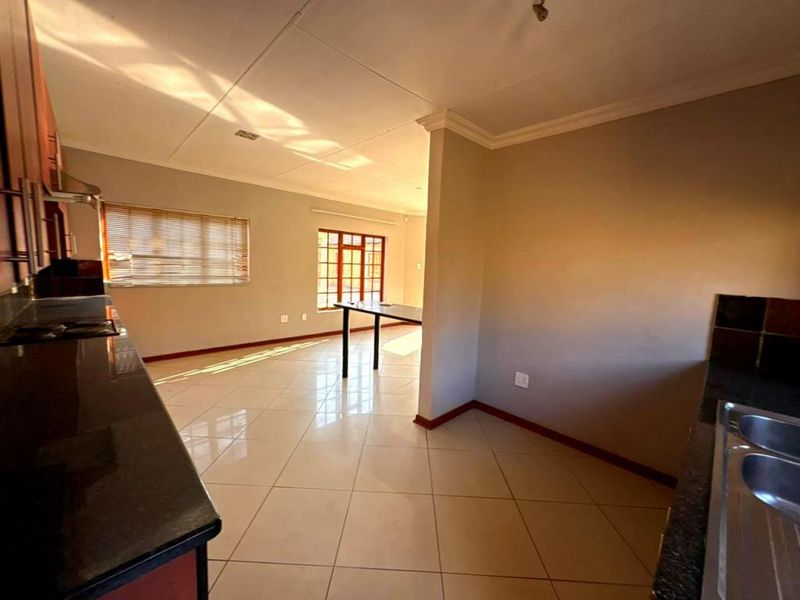 Spacious open-plan kitchen and living area featuring tiled flooring, built-in cabinetry with granite countertops, and a breakfast bar.