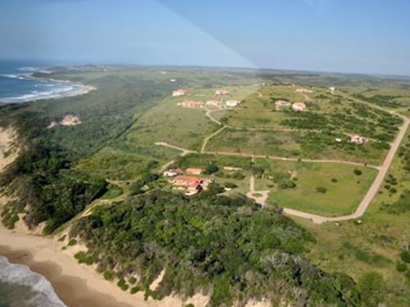 An aerial view of a coastal residential estate featuring established road infrastructure and scenic oceanfront positioning.