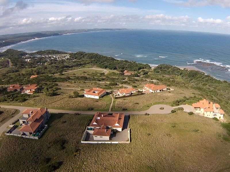 An aerial view of a coastal residential estate featuring multiple homes situated on expansive, naturally landscaped grounds overlooking the ocean.
