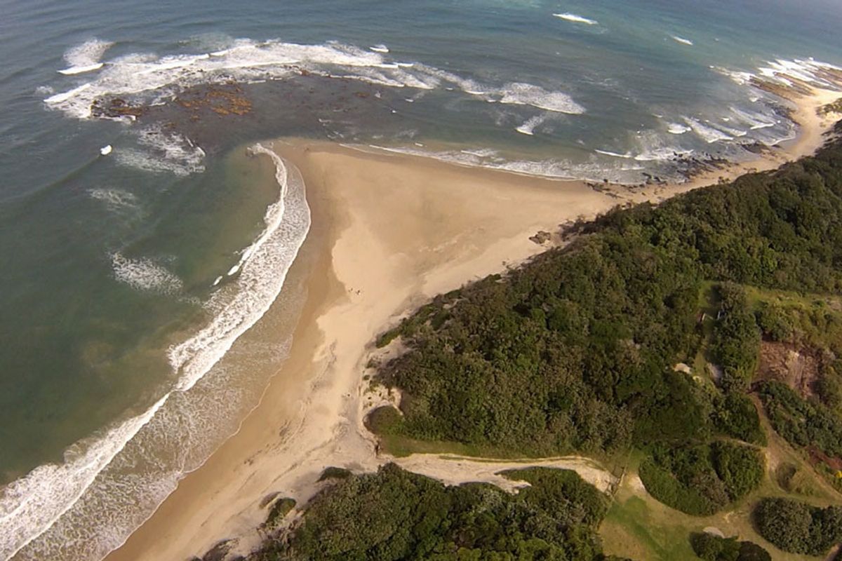 An aerial view of the coastal property, showcasing direct beach access and surrounding natural landscape.