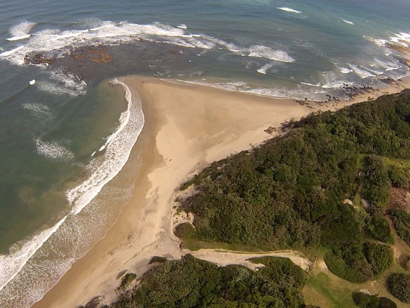 An aerial view of the coastal property, showcasing direct beach access and surrounding natural landscape.