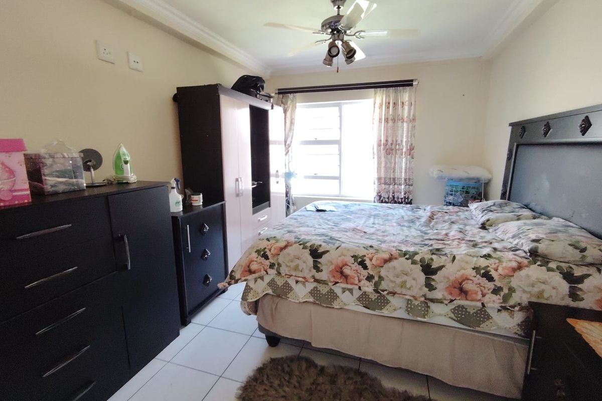 A bedroom featuring tiled flooring, a ceiling fan, and a window with natural light.