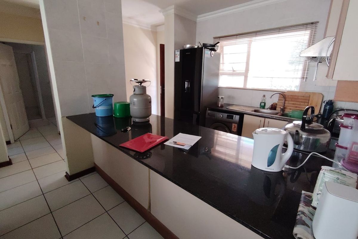 A functional kitchen featuring a black granite breakfast bar, tiled flooring, and integrated cabinetry with a window overlooking the exterior.