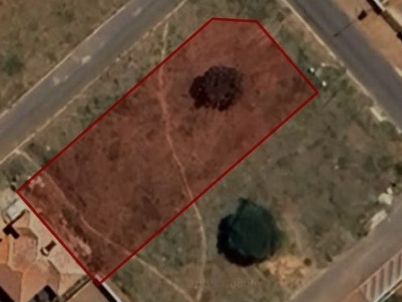 An aerial view of a vacant residential corner plot, highlighting the property boundaries and existing vegetation on the site.