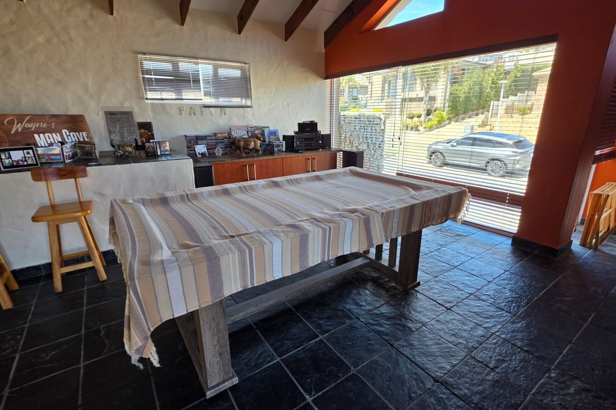 Spacious living area featuring vaulted ceilings with exposed timber beams, slate tile flooring, and large glass sliding doors providing ample natural light.