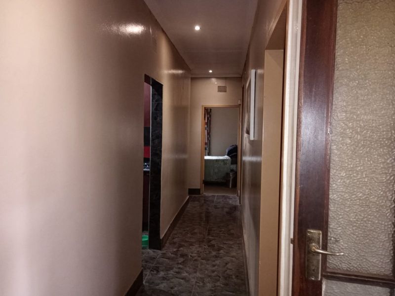 A functional hallway featuring tiled flooring and recessed downlighting, providing access to adjacent rooms within the home.