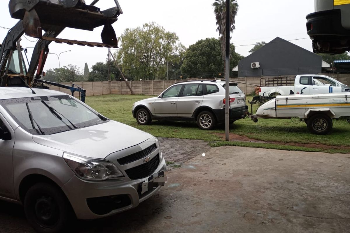 View of a rear yard area featuring a concrete patio, perimeter wall, and open lawn space.