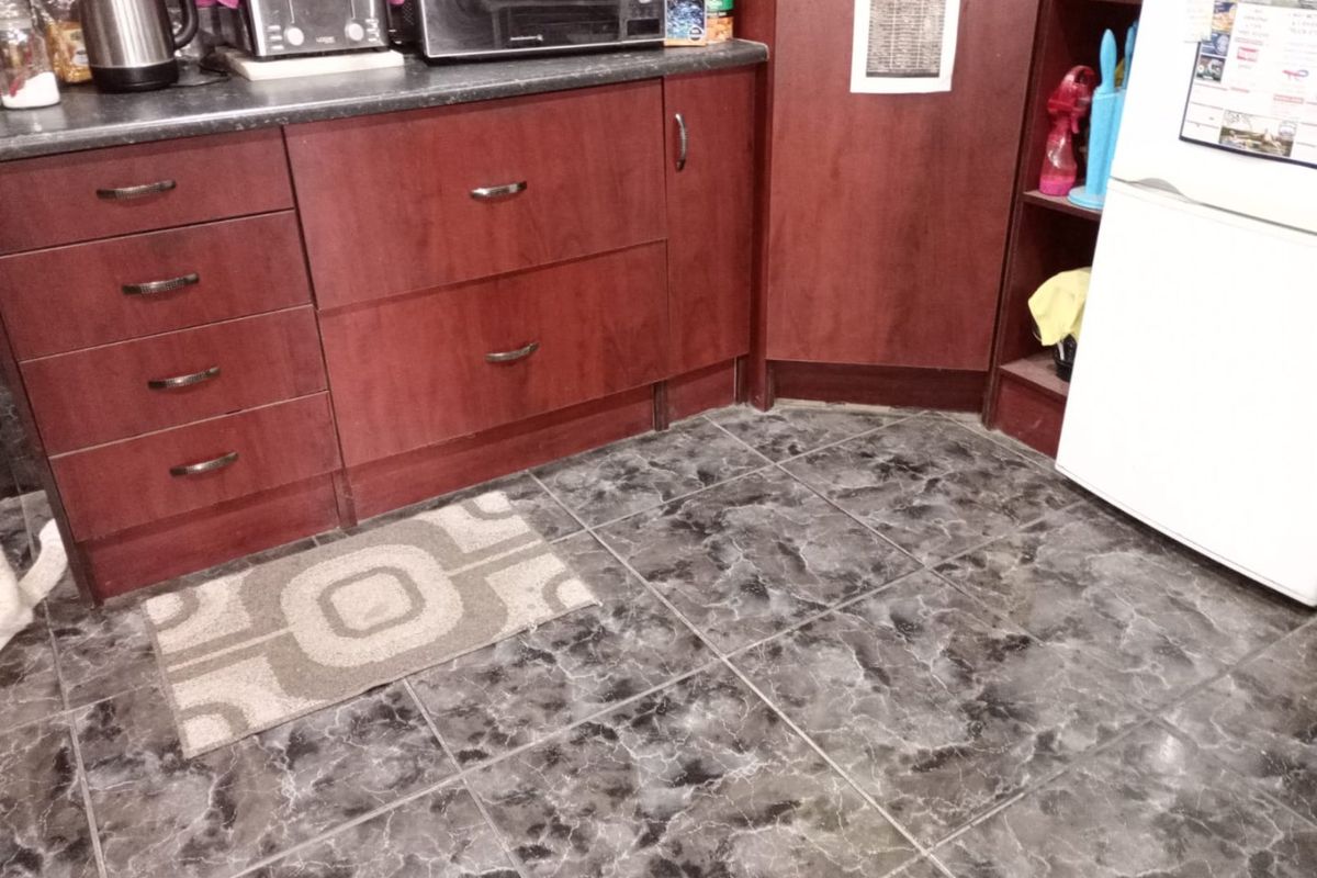 A kitchen area featuring dark wood-look cabinetry, laminate countertops, and patterned ceramic floor tiles.