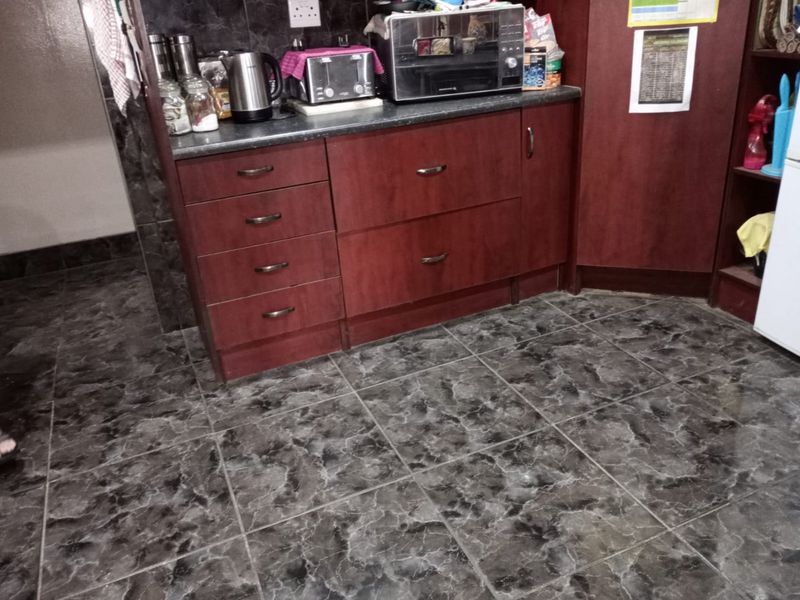 A kitchen area featuring dark wood-look cabinetry, a laminate countertop, and dark patterned floor tiles.