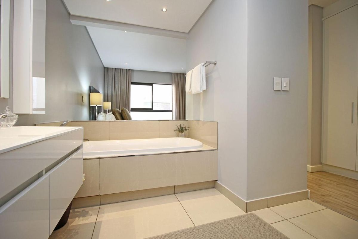 Modern bathroom featuring a built-in bathtub, sleek vanity cabinet, tiled flooring, and integrated storage cupboards in a clean, well-maintained space.