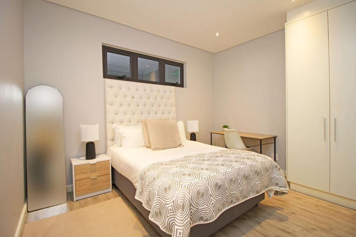 A well-maintained bedroom featuring neutral tones, built-in wardrobes, recessed lighting, and modern laminate flooring.