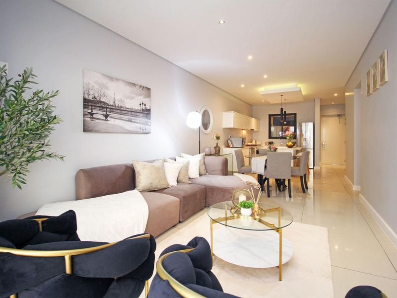 A modern open-plan living and dining area featuring sleek porcelain tiles, recessed lighting, and a seamless transition to a contemporary kitchen space.