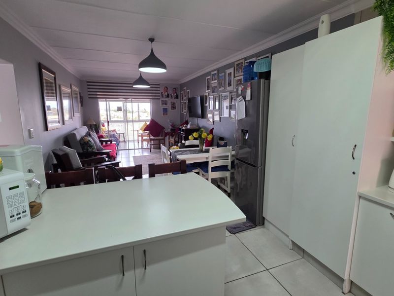 Open-plan living and kitchen area featuring tiled flooring, modern cabinetry, and a sliding door leading to an outdoor balcony space.