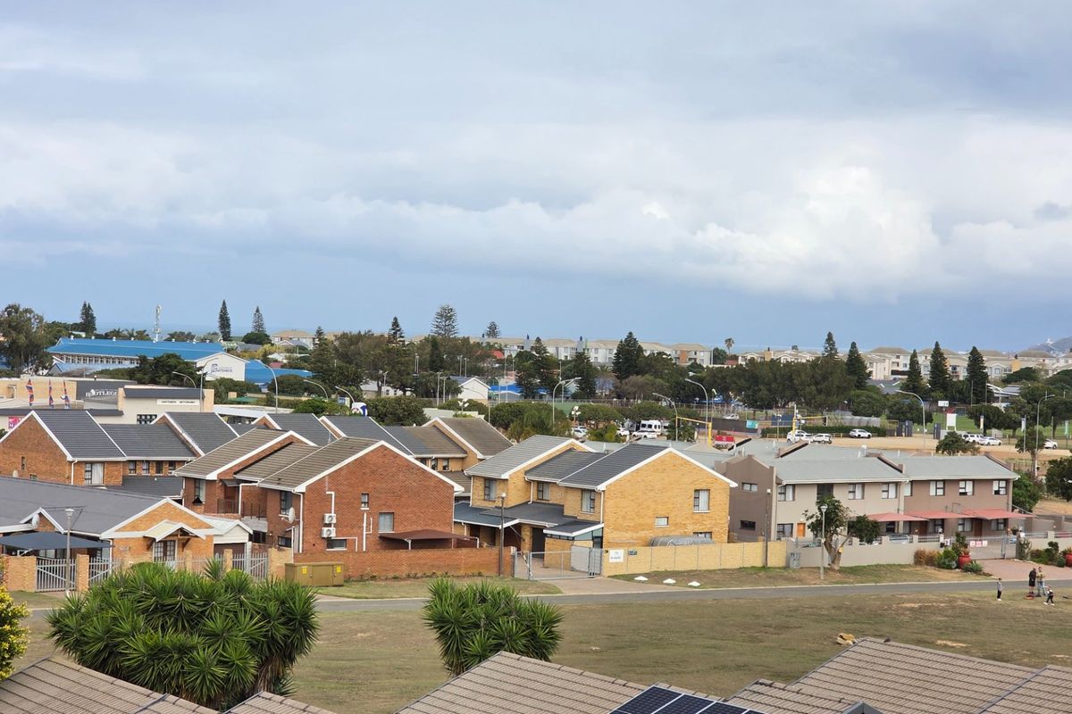 An elevated aerial view of a residential apartment complex featuring brick buildings with tiled roofs and surrounding landscaped grounds.
