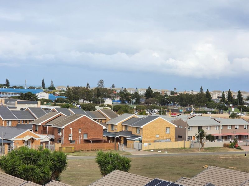 An elevated aerial view of a residential apartment complex featuring brick buildings with tiled roofs and surrounding landscaped grounds.