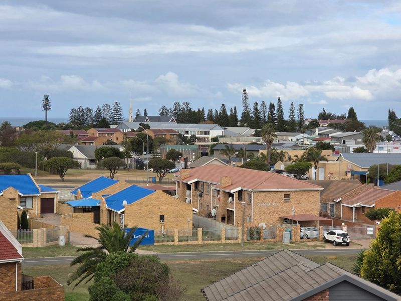 An elevated view overlooking a residential neighbourhood with various apartment complexes and houses under a cloudy sky.