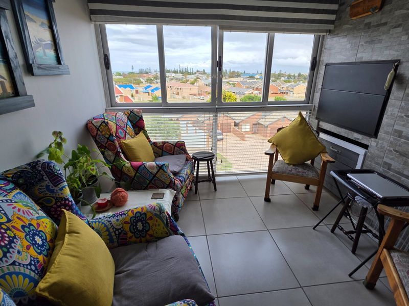 Enclosed balcony featuring tiled flooring, large windows with neighborhood views, and a decorative stone-cladding feature wall.