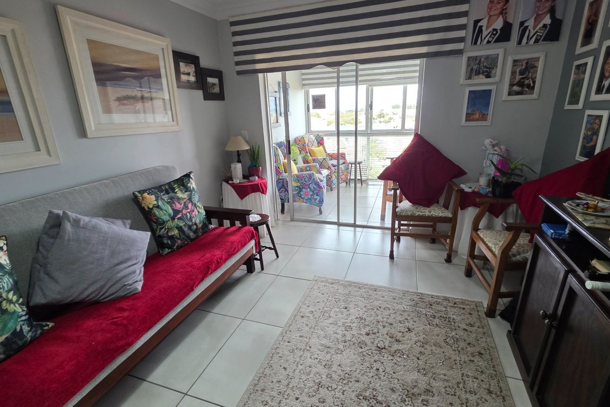 A living room featuring ceramic floor tiles and a sliding glass door providing access to an outdoor balcony area.