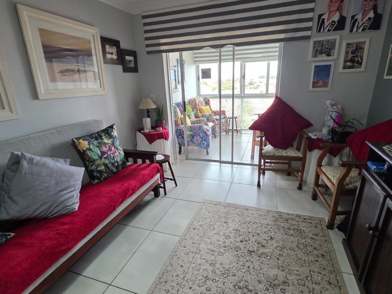A living room featuring ceramic floor tiles and a sliding glass door providing access to an outdoor balcony area.