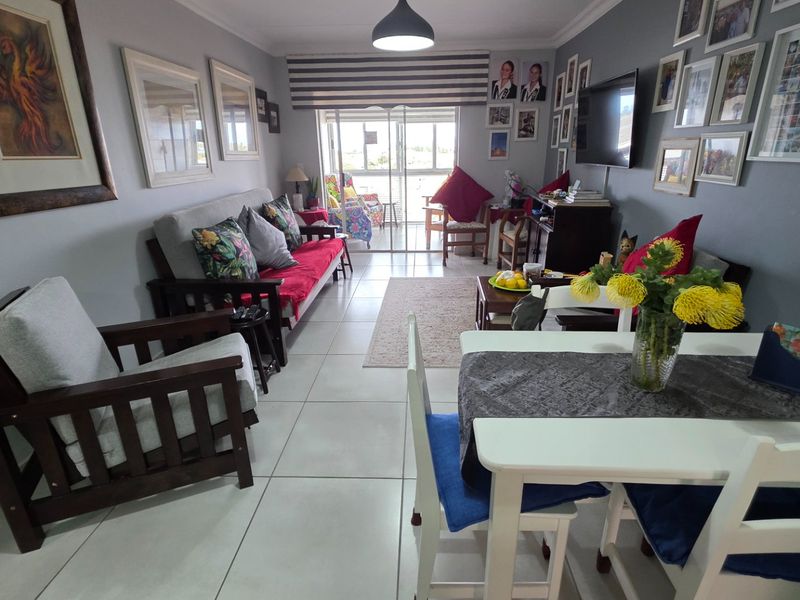 Open plan living and dining area featuring tiled flooring, neutral walls, and a sliding glass door leading to an outdoor balcony space.