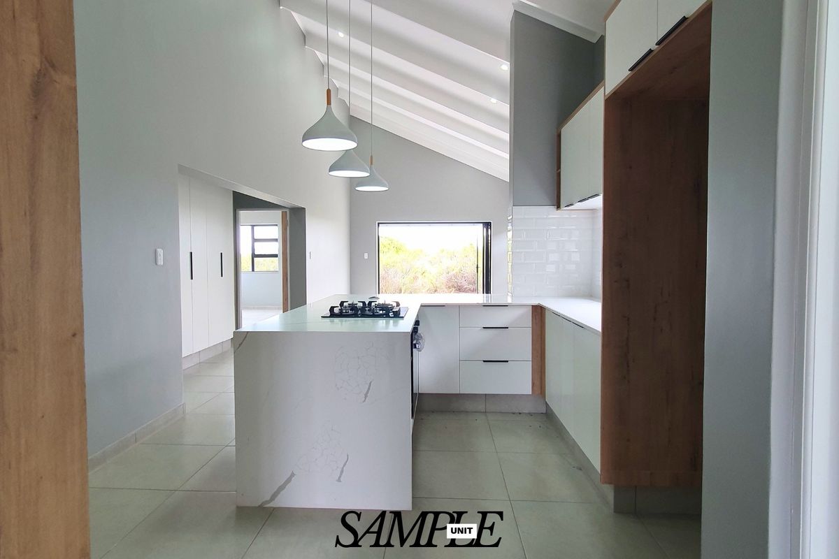 Modern kitchen featuring a central island with a gas hob, sleek white cabinetry, subway tile backsplash, and a high vaulted ceiling.