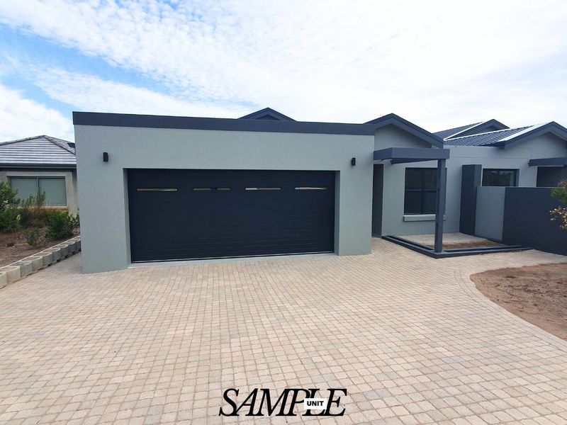 Modern front elevation featuring a paved driveway, automated garage door, and a covered entrance with contemporary grey facade finishes.