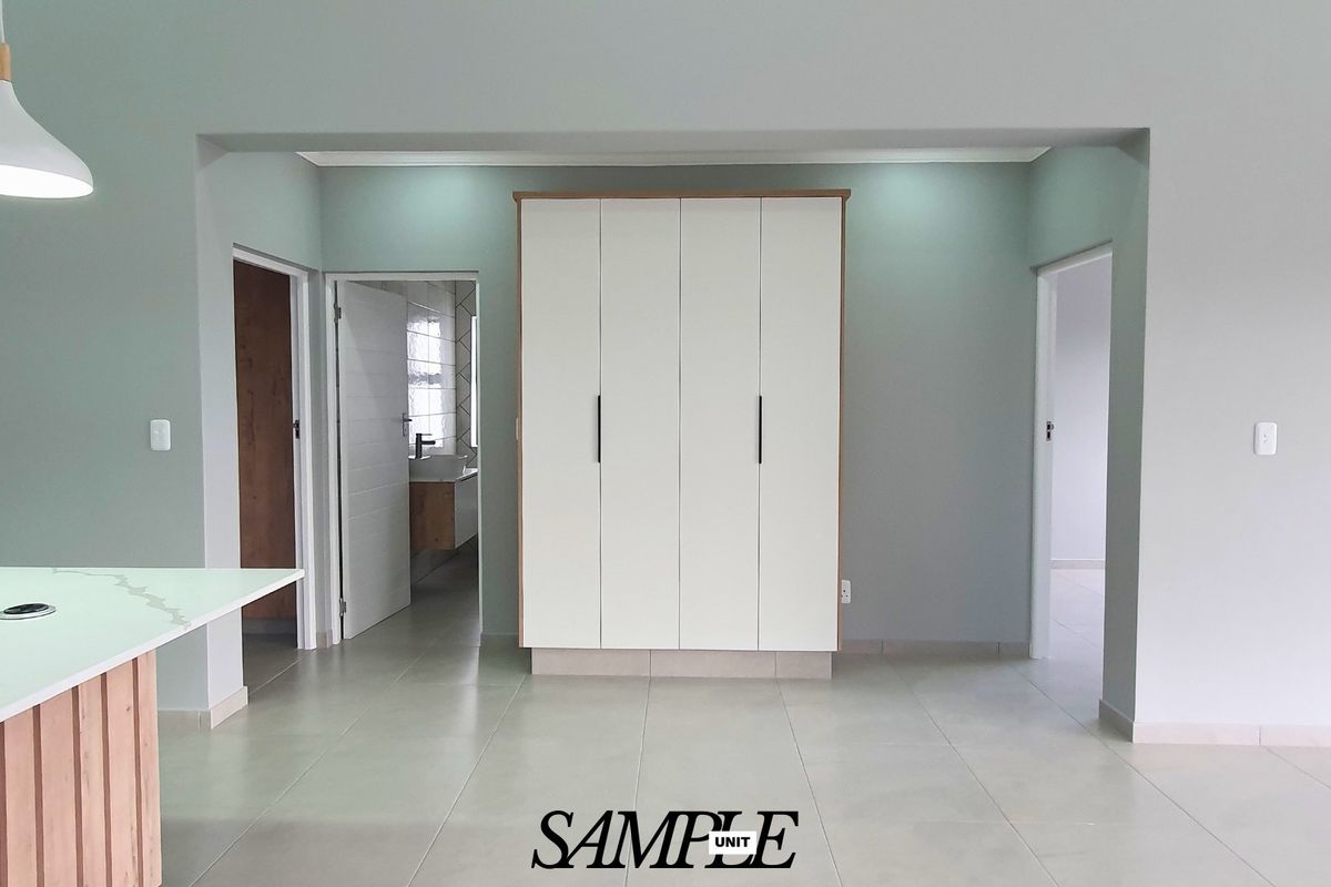 A clean, modern bedroom featuring neutral tiled flooring, built-in wardrobes, and recessed lighting, offering a bright and minimalist living space.