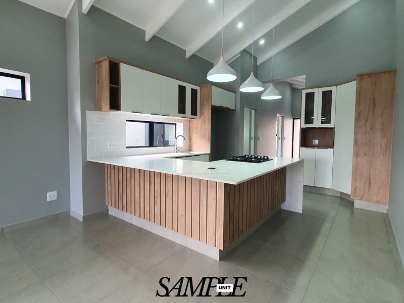 Modern kitchen featuring light wood and white cabinetry, stone countertops, gas hob, vaulted ceilings, and contemporary pendant lighting in an open-plan layout.