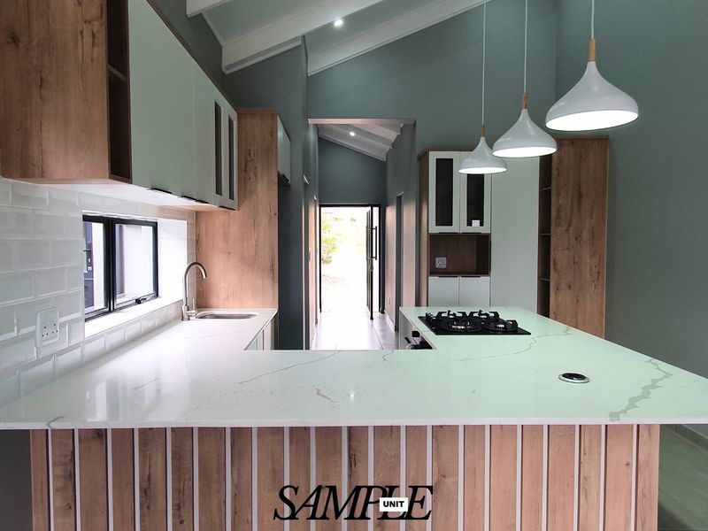 Modern kitchen featuring quartz countertops, a gas hob, subway tile backsplash, and custom cabinetry under a vaulted ceiling with pendant lighting.