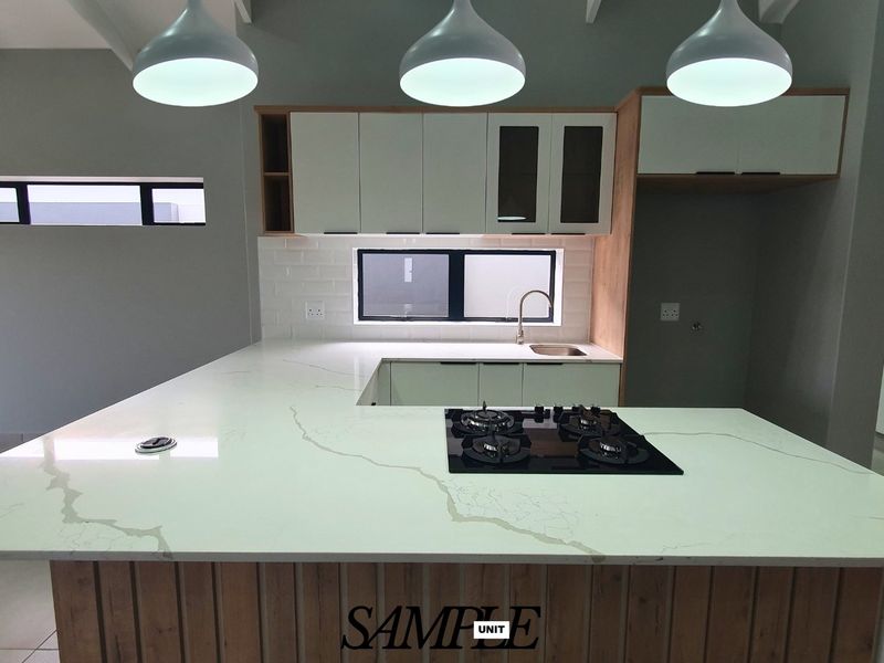 Modern kitchen featuring a large quartz island with integrated gas hob, subway tile backsplash, and contemporary cabinetry with pendant lighting.