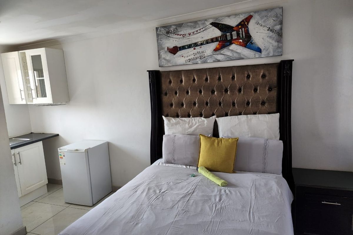 A bedroom featuring a kitchenette area with built-in cabinetry and tiled flooring, offering a compact living space.